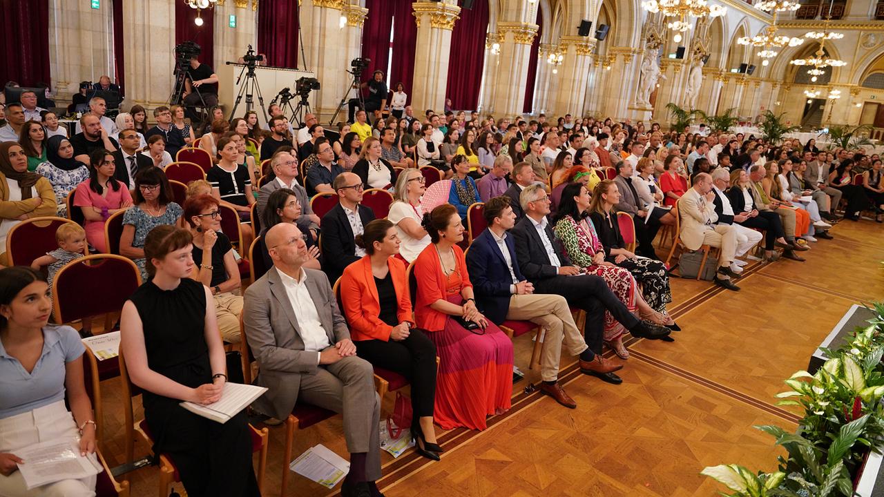 Man sieht das sitzende Publikum der Abschlussfeier im Wiener Rathaus 